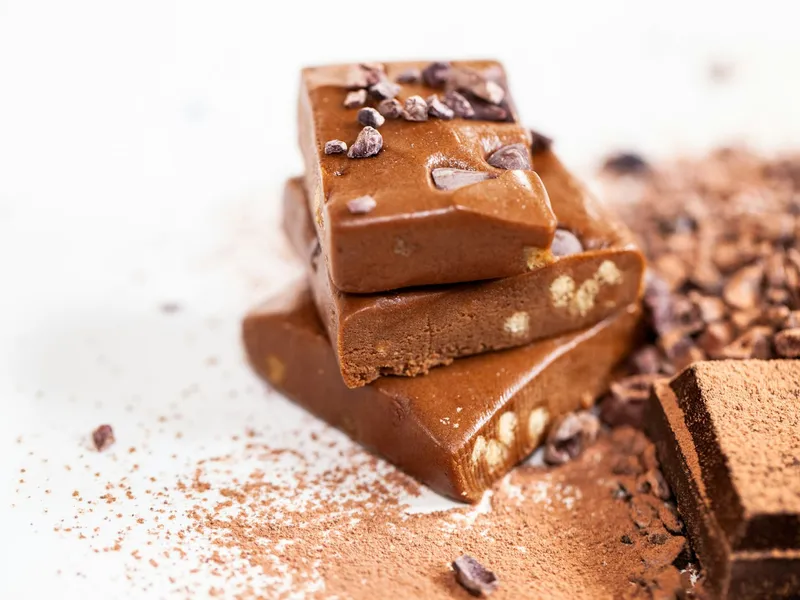 Barras de chocolate empilhadas sobre cacau em pó e nibs de cacau