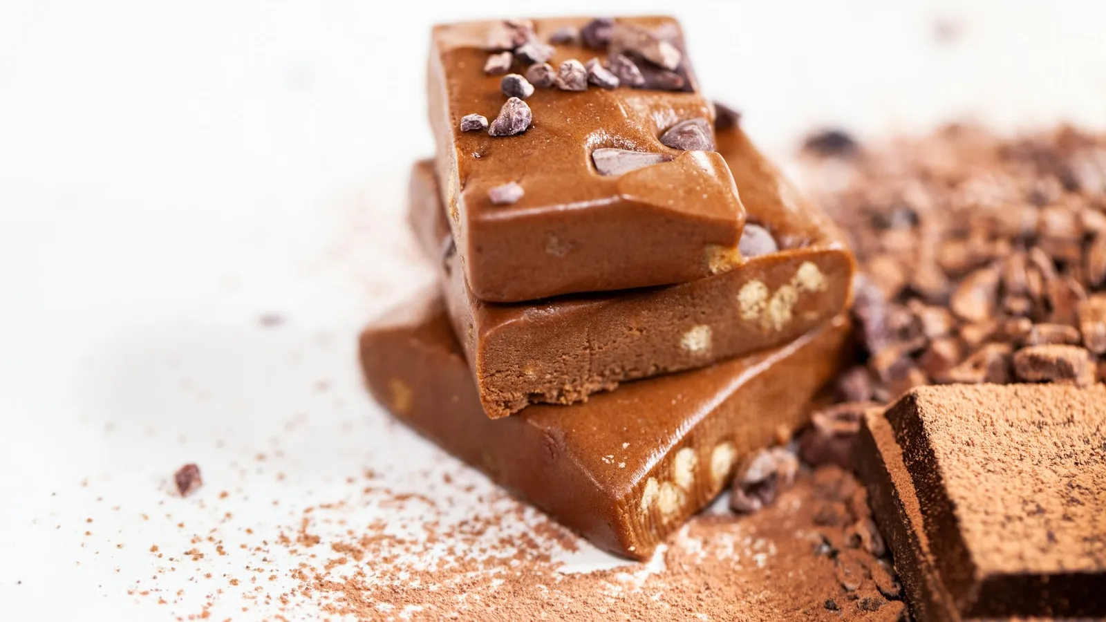 Barras de chocolate empilhadas sobre cacau em pó e nibs de cacau