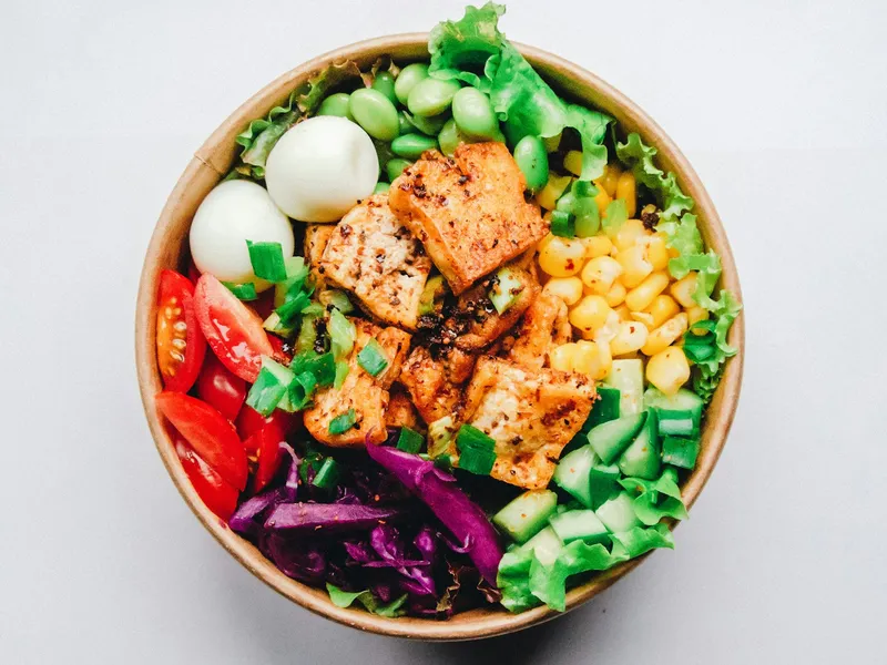 Bowl com tofu dourado, edamame, milho, ovos de codorna, tomate, pepino e repolho roxo